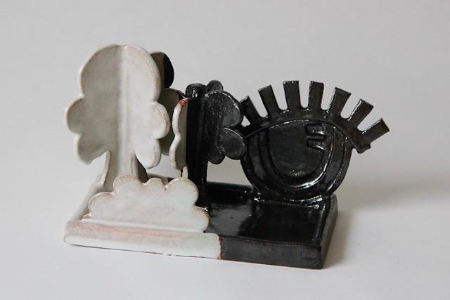 A ceramic tableau on a shared base: a white tree with a cloud-like canopy facing a glossy black bird with a radiating crest and an enigmatic smile — a folk-tale encounter between innocence and the trickster