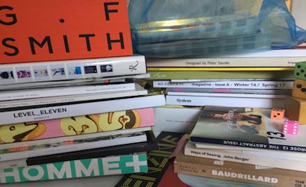 A dense stack of art, fashion, and theory publications in daylight: Ways of Seeing, Baudrillard, System — a cross-disciplinary library of influences