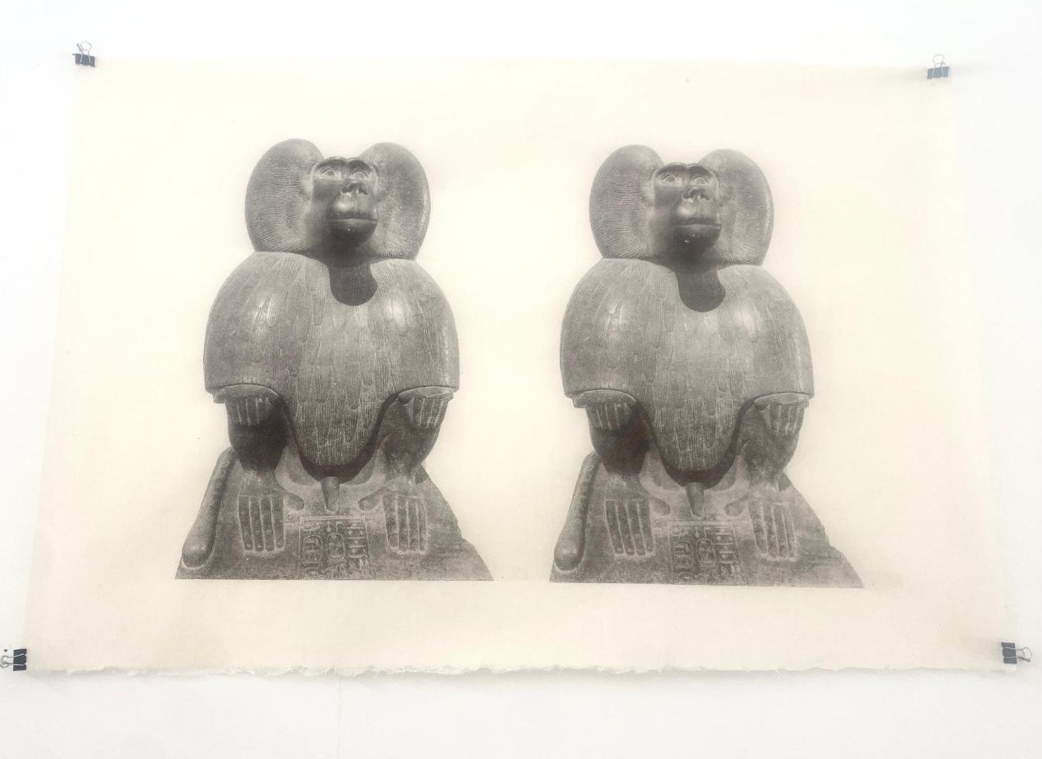 Two identical screen prints of Thoth depicted as a baboon — seated, hands on knees, wings folded at the shoulders — hung side by side with bulldog clips on a white wall