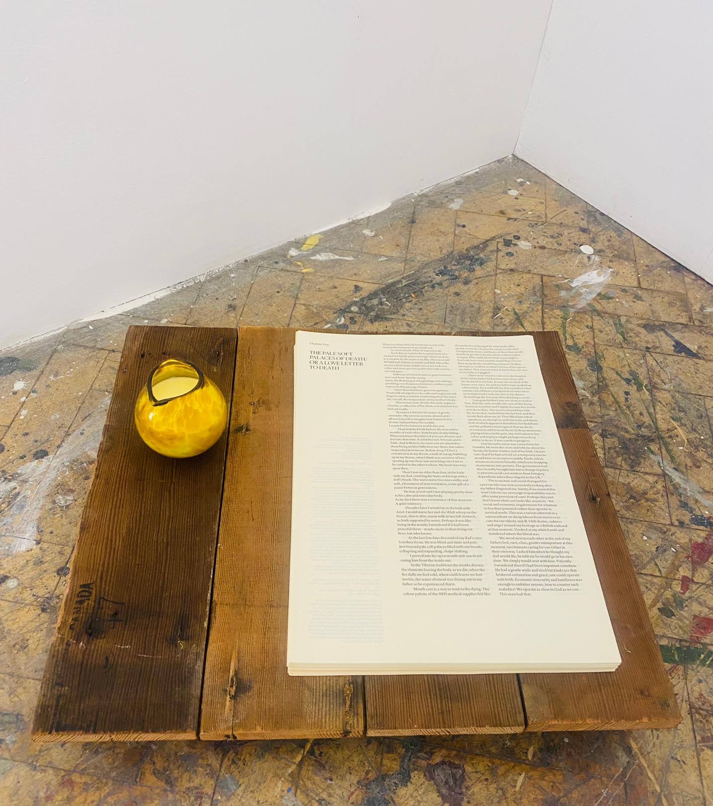 Close-up of the floor piece - the open essay on reclaimed wooden boards with amber glass jug